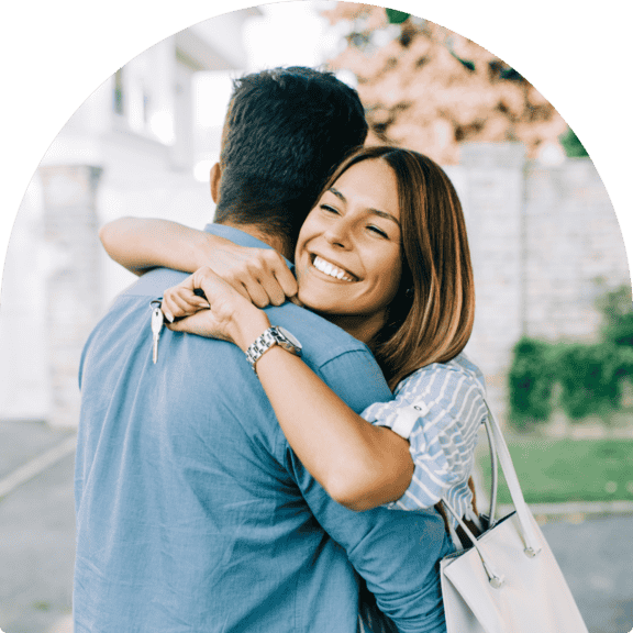 Smiling wife holding keys while hugging husband, celebrating new home